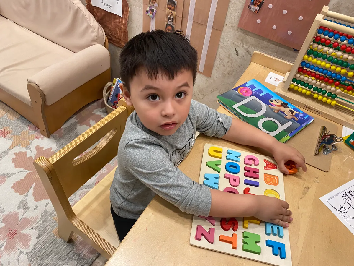 A child fitting colorful letters into an alphabet puzzle